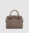 A taupe brown suede handbag with dual top handles, a front slip pocket, and a small silver-tone diamond-shaped logo clasp, shown against a light gray background.