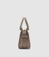 A side view of a taupe brown suede handbag with a double top handle and a front strap detail.