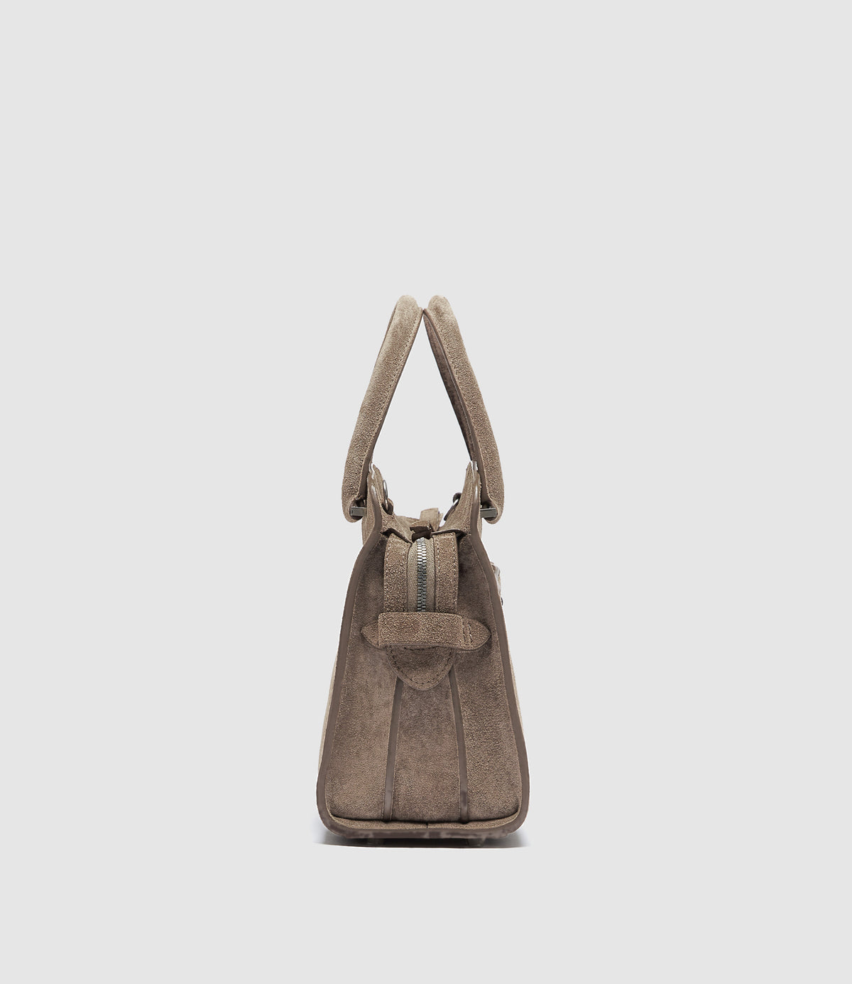 A side view of a taupe brown suede handbag with a double top handle and a front strap detail.